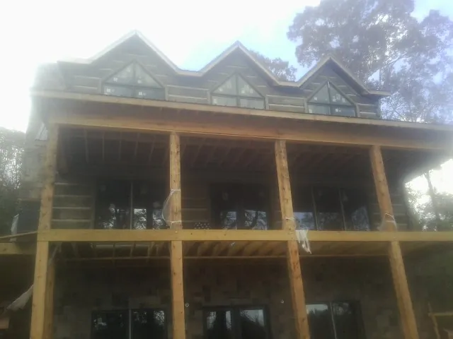 Dormers and porch framing on a large log home under construction — Roof Coating work by our crew in Afton